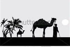 man with camels and palm trees silhouetted against the sky in black and white