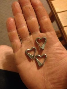 a person's hand holding three metal hearts