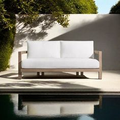 a white couch sitting on top of a swimming pool next to a lush green tree