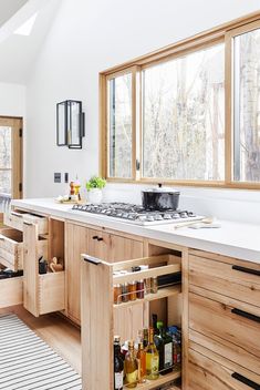 a kitchen with wooden cabinets and white counter tops in front of a large open window