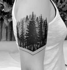 a woman with a tattoo on her arm and trees in the forest behind her back