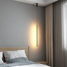 a bed sitting next to a window with curtains on both sides and a light hanging from the ceiling