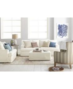 a living room with white furniture and blue accents