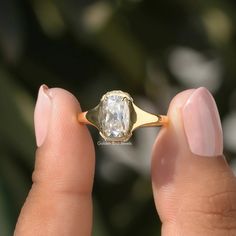 a woman's hand holding an engagement ring with a large diamond in the center