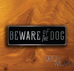 the beware of the dog sign is on top of a wooden surface with wood grain