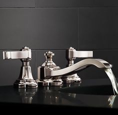 two chrome faucets on a black counter top