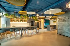 an empty bar with lots of chairs and plants hanging from the ceiling in a restaurant