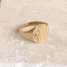 A vintage 9 carat gold signet ring with a engraved detailing in the corner. This charming piece has a great shape and a small amount of detailing on the corner of the face.CONDITION: Wear consistent with age and use. Please see photos for more detail.ASSAYED IN BIRMINGHAM, MADE CIRCA.1987APPROX. BAND WIDTH (SMALLEST): 2.5mmAPPROX. FACE SIZE: 12mm x 11mmRING SIZE: UK: R | US: 8 1/2WEIGHT: 2.1g Vintage Yellow Gold Signet Ring With Polished Finish, Vintage Gold Initial Ring With Polished Finish, Antique Rectangular Engraved Signet Ring, Vintage Yellow Gold Rings With Engraving Option, Vintage Tarnish Resistant Signet Ring For Formal Occasions, Antique Gold Engraved Promise Ring, Vintage Engraved Yellow Gold Signet Ring, Antique Hallmarked Signet Ring For Promise, Gold Vintage Initial Ring For Formal Occasions