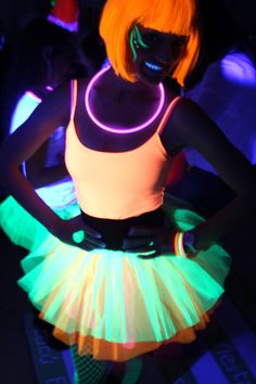 a woman with neon lights on her body wearing a skirt and glow makeup in the dark