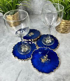 three wine glasses sitting next to each other on top of a table with plants in the background