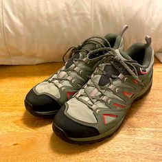 a pair of shoes sitting on top of a hard wood floor next to a pillow