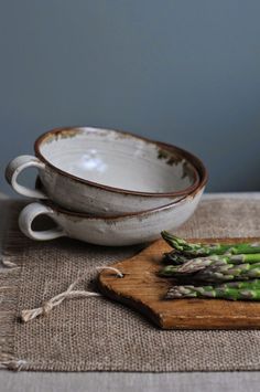 asparagus on a cutting board next to two bowls