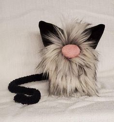 a stuffed animal with a pink nose laying on a white bed sheet next to a black leash