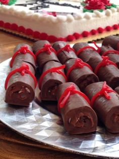 there are many pieces of chocolate wrapped in red ribbon on the plate next to the cake