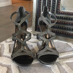 a pair of silver high heeled shoes sitting on top of a rug next to a mirror