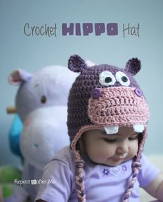 a baby wearing a crochet hipo hat sitting in front of stuffed animals