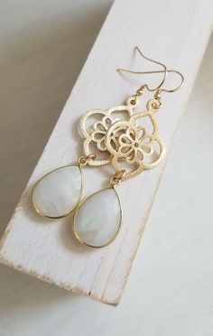 Make a unique statement on your Wedding Day in these gorgeous Moonstone teardrop earrings. Earrings consist of a modern design brushed gold flower that is accented with a natural bezel set faceted Moonstone. Details: * Brushed Gold Flower Measures about 28 mm * Each flower is 14 k gold plated on brass,. Lead, nickel and cadminum free with a non tarnishing coat * Natural teardrop bezel set faceted Moonstone measuring about 18 mm * 14 k Gold Filled Ear Wires (not plated) * Earrings measure a littl Bride Earrings Gold, Jewelry For Bride, Boho Wedding Earrings, November Birthstone Necklace, Wedding Day Jewelry, Citrine Necklace, Bride Earrings, Moonstone Bracelet, Jewelry Statement