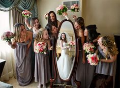 a group of bridesmaids pose for a photo in front of a large mirror