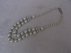 A heavy faux pearl necklace.  This necklace is made of sixty (60) spherical beads tightly strung on a strong necklace thread, with a two strand swag at the front. The beads are made of glossy white plastic with a shimmering pearly finish, they are designed to look like large fake pearls. The beads come in three sizes, 7mm for the smallest, 12mm for the medium size ones and 15mm for the largest. The beads are each separated from the next by shining silver coloured spacer beads. The necklace has a Necklace Thread, Theatre Props, Necklace Dress, Learn How To Knit, String Of Pearls, Jewelry White, Sewing Baskets, Dressing Up, Faux Pearl Necklace