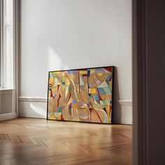 an abstract painting on the wall in a room with hard wood floors and white walls