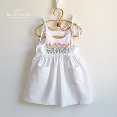 This adorable dress is perfect for little ones during the warm spring and summer days. Made of linen, a cool and comfortable material, the dress features a delicate and charming design with hand-embroidered flowers, adding a touch of craftsmanship and elegance. Features: Material: High-quality linen and cotton, ideal for keeping your little one cool and comfortable in the heat. Design: Beach dress in white, cream, and beige tones, combining simplicity and style. Details: Hand-embroidered flowers Spring Vacation Embroidered Sundress, Summer Cotton Sundress For Babies, Spring Beach Sundress With Floral Embroidery, Cute Linen Beach Dress, White Cotton Sundress For Spring, White Floral Applique Dress For Summer, White Sundress For Summer, Cute Linen Summer Dress, Embroidered Summer Sundress For Spring