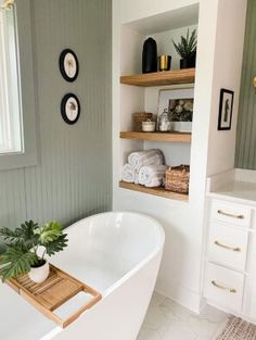 a white bath tub sitting in a bathroom next to a sink and mirror on the wall