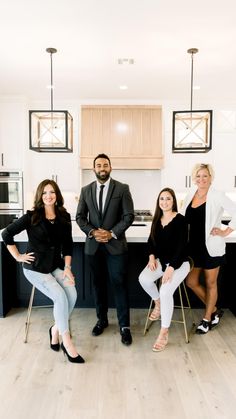 three women and one man are sitting in front of the kitchen counter, posing for a photo