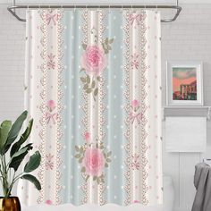 a shower curtain with pink roses and polka dots on it, next to a potted plant