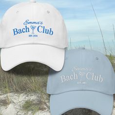 two hats sitting on top of each other in the sand near some grass and sea oats