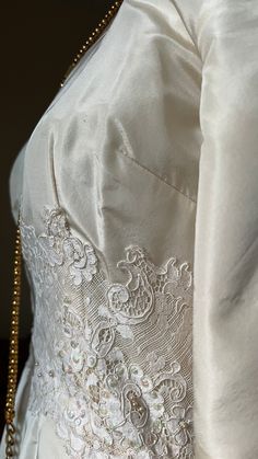 the back of a white wedding dress with gold beading on it's waist