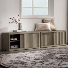 a living room with a rug, window and storage cabinets in it's corner