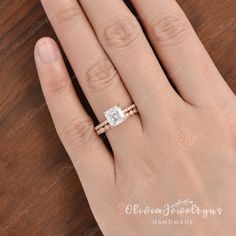 a woman's hand with a diamond ring on top of her finger and the other hand holding an engagement ring