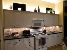 a kitchen with white cabinets, black counter tops and an oven in the center area