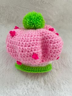 a crocheted pink and green hat with pom - pom on top