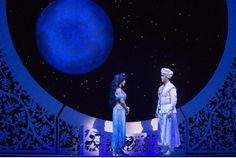 two people standing on stage in front of a large blue object with stars above it