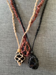 two necklaces with different colored beads on a gray surface, one is black and the other is brown