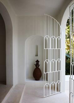 a vase sitting on top of a white shelf next to a wall covered in arches