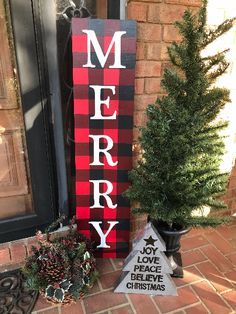 a merry sign sitting next to a christmas tree and potted plant on the front porch