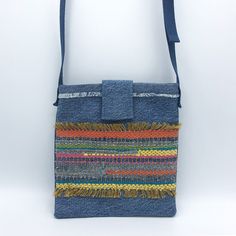 a blue bag with multicolored stripes and fringes on the front, hanging from a strap