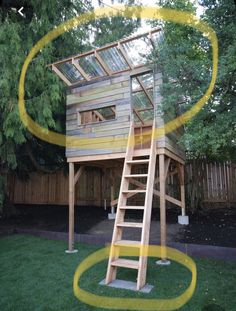 a tree house built into the side of a yard with a ladder leading up to it