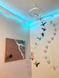 some birds are hanging from the ceiling in a room with white walls and blue lights