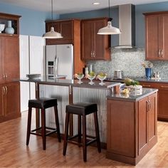 a large kitchen with wooden cabinets and stainless steel appliances, along with two bar stools