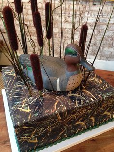 a duck sitting on top of a cake covered in frosting and grass sticks with feathers sticking out of it