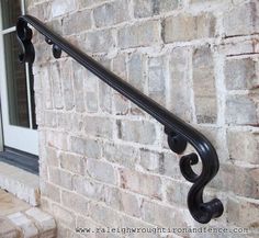 an iron hand rail on the side of a brick building