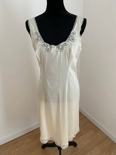 This is a beautifully feminine French below knee lingerie Slip. Made by HELIOS, Paris. 1950's Quality French lingerie. Fabric - Nylon. Shimmering oyster white satin fabric with floral lace trim around the neckline and hem. No size label. I would estimate a 'Large'. Measurements laid flat: Below the Bust 43cm Hips 56cm Length 96cm (from top of shoulder strap to hem) 'New Old Stock' Unworn - fabulous condition. No tags. Elegant Sleeveless Nightgown For Home, Feminine Fitted Nightgown For Home, Elegant Cream Sleeveless Nightgown, Elegant Sleeveless Cream Nightgown, Fitted Cream Nightgown For Wedding, Fitted Sheer Cream Nightgown, Vintage Cream Sleeveless Sleepwear, Summer Wedding Fitted Chemise, Fitted Sleeveless Chemise For Wedding