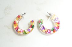 Fun and lightweight multi color shell and resin hoop earrings. The hoop measures 1.75" across and the earring is .25" thick. The post is made of zinc alloy. The earring backer is surgical steel. All DLD jewelry comes in a silver jewelry box for gift giving. We use the highest quality findings to ensure a piece that will last for years to come. DLD jewelry comes with a lifetime guarantee.Dana LeBlanc Designs- Handmade Jewelry Resin Hoop Earrings, Box For Gift, Artsy Aesthetic, Silver Jewelry Box, Multicolor Earrings, Polish Silver, Colorful Earrings, Shell Earrings, Large Earrings