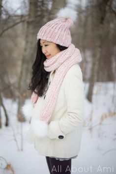 a woman standing in the snow wearing a pink hat and scarf