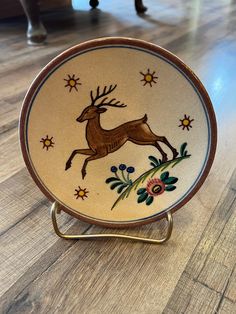 a decorative plate with a deer on it is sitting on a wooden floor next to a chair