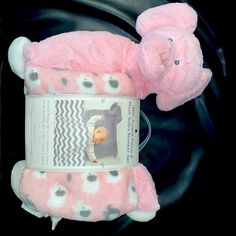 a pink teddy bear laying on top of a black blanket next to a magazine holder