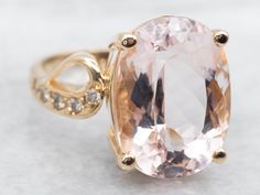 an oval shaped morganite and diamond ring on a white surface with gold plating